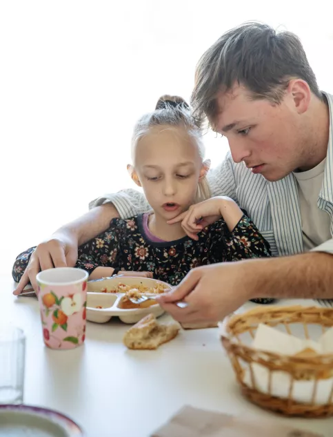 Le moment du déjeuner entre un éducateur et une petite fille