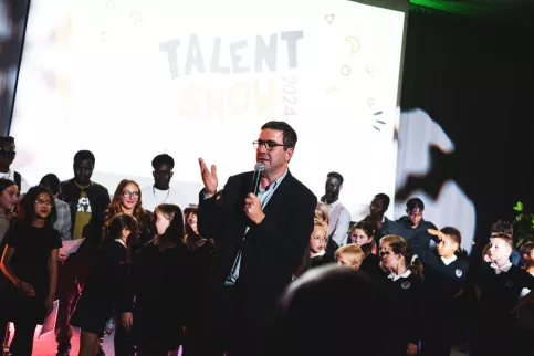 Un directeur au micro félicitant les jeunes aux Talents show