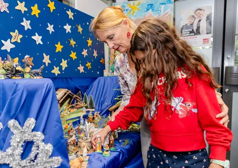 Bérengère Mazerbourg, animatrice pastorale avec une enfant devant la crèche