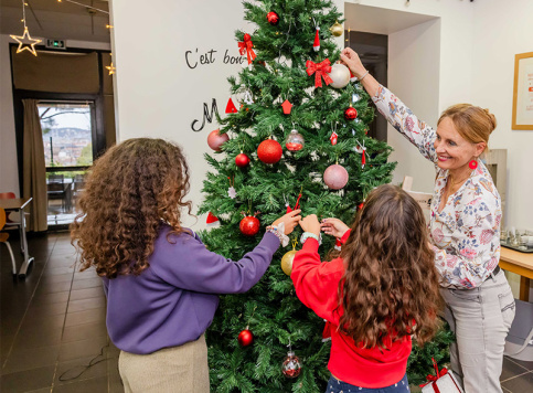 Bérengère Mazerbourg, animatrice pastorale aide 2 enfants à décorer le sapin 