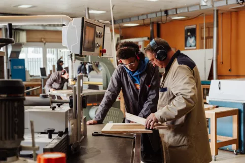 un jeune et son prof dans l'atelier de menuiserie