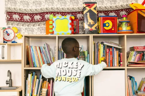 jeune enfant (de dos) devant une bibliothéque de livres