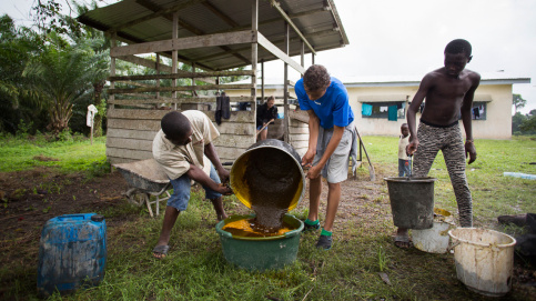 Thomas et un ouvrier agricole du foyer transvasent l’huile de palme qu’ils viennent de presser. Photo : P. Besnard