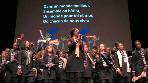 Des chansons entraînantes, chantées avec coeur par les jeunes choristes. En arrière-plan, le texte qui permet à tous de participer. (c) Laetitia Notarianni