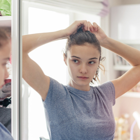 Jeune fille se regardant dans la glace de sa chambre
