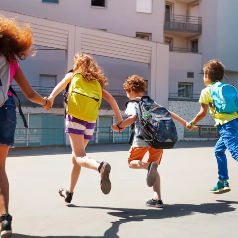 Elèves de dos courant devant leur école