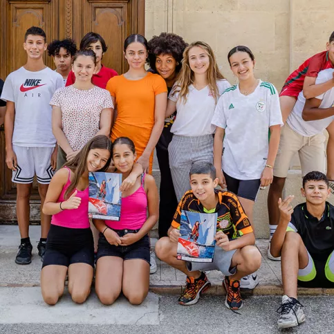 Violette Dorange pose devant le collège au milieu d'une quinzaine de jeunes élèves