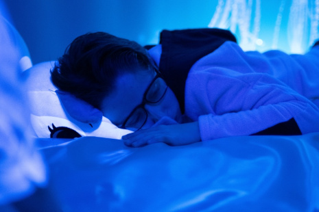 jeune garçon sur un lit dans une atmosphère bleutée