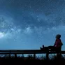 Jeune femme assise sur un banc regardant un ciel étoilé